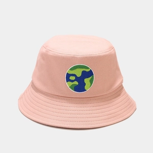 Detail of a pink bucket hat showing a circular embroidered globe patch and twill cotton fabric