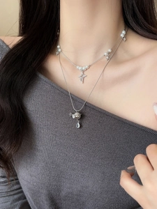 Close-up of double-layer necklace with pearl beads, star charms and Saturn pendant