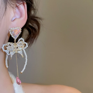 Detail of luxury butterfly drop earrings with pink crystals and pearls on a model