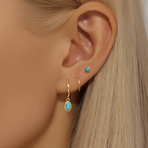 Macro detail of vintage gold hoop earrings with turquoise and opal stones on model ear