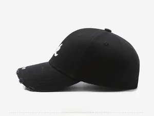 Detail view of distressed black baseball cap with white rabbit embroidery and torn brim