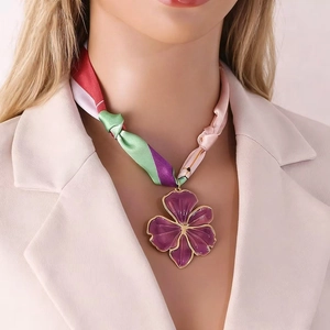 Detailed view of a purple flower pendant necklace with a colorful silk scarf band.