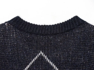 Detailed view of rib-knit round neck and diamond pattern on dark knit sweater