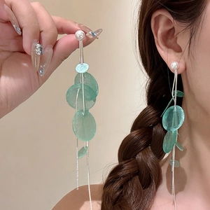 Detail of silver tassel earrings with white pearls and green translucent round pendants