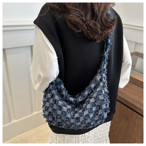 Detail of blue and white checkered denim crossbody bag with frayed fringe texture