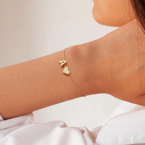 Close-up of a gold-toned stainless steel bracelet with heart and letter A charms