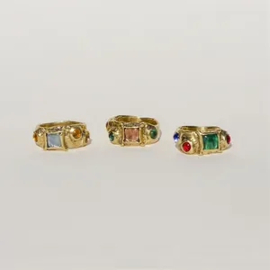 Close-up of three chunky gold rings set with six colorful stones in a vintage style