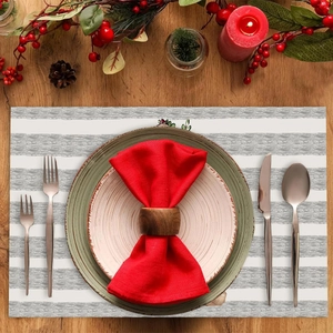 Christmas table setting with striped heat-resistant placemat, red berries and holiday decor