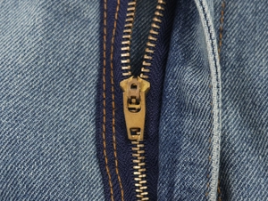 Close-up of premium brass zipper on classic blue denim midi skirt with visible twill texture