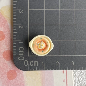 Miniatur-Lebensmittelmodell einer Schüssel mit orangefarbener Suppe und Größenskala
