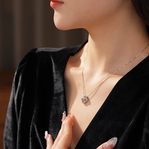 Detail of silver clover flower necklace with sparkling zircon worn on black velvet top