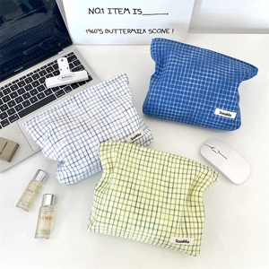 Three plaid fabric pouches in blue and yellow shown with a laptop for travel storage