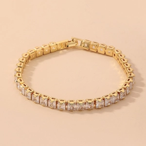 Macro detail of gold-plated tennis bracelet featuring square-cut princess cubic zirconia