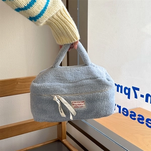 Detail of light blue plush makeup bag showing soft lamb wool texture and zipper strap