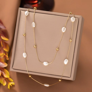 Detailed close-up of double-layered gold chain with baroque pearls and polished metal beads