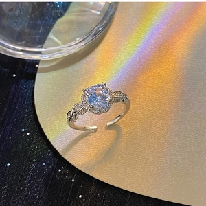 Macro shot of silver ring with round zircon, twisted band and sparkling rainbow light