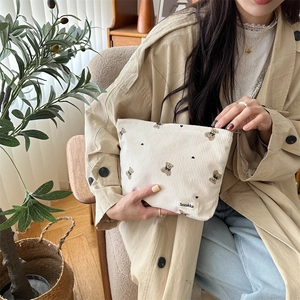 Detail of cute bear embroidery on beige corduroy pouch with a sturdy metal zipper