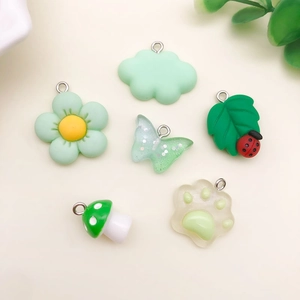 Draufsicht auf grüne Harzanhänger wie Schmetterling und Katzenpfote für DIY-Schmuck
