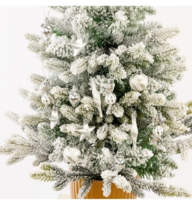 Detailed view of silver Christmas ornaments including stars and balls on a snowy tree