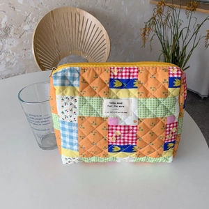 Dettaglio della borsa trucco patchwork trapuntata multicolore con cerniera gialla e fiori