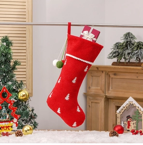 Detail of red Christmas stocking with tree embroidery and festive gift box inside