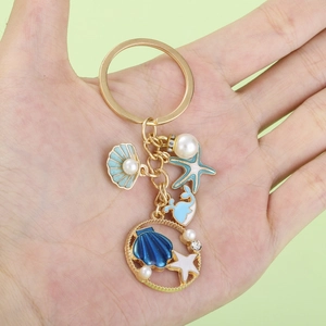 Goldener Schlüsselanhänger mit blauen Emaille-Seesternen, Delfinen und Muscheln mit Perlen