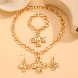 Detail of golden cross jewelry set with spiral texture on necklace and earrings
