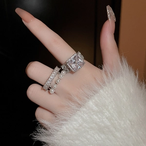 Gros plan sur un ensemble de bagues en zircon et perles blanches sur un pull blanc doux