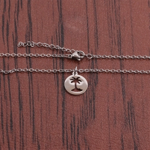 Detail shot of a polished hollow coconut tree pendant on a classic O-chain necklace
