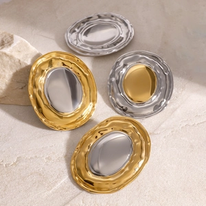 Two-tone gold and silver oval earrings with rippled texture on a natural stone background