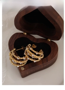 Detail of gold triple-layered twisted hoop earrings with crystals in a heart wooden box
