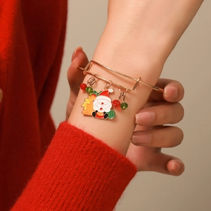 Close-up of golden Christmas bracelet with Santa enamel charm and festive beads on wrist