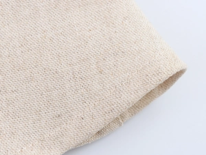 Vista macro che mostra la trama del lino beige naturale e le cuciture dettagliate dell'abito