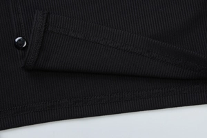 Detailansicht der schwarzen gerippten Strickstruktur und Knopfdetails an einem Damenoberteil