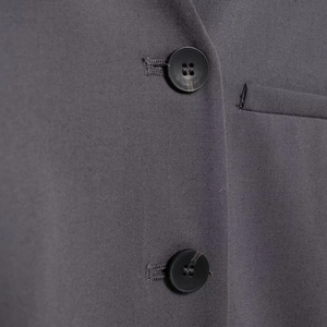 Close-up of charcoal gray urban commuter vest with premium textured fabric and buttons