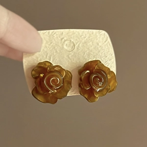 Close-up of amber resin flower earrings with swirl patterns on a neutral beige card