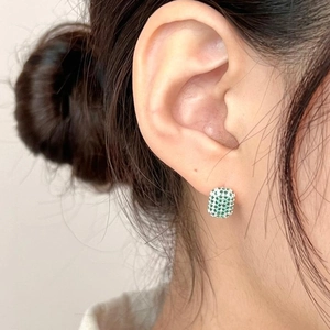 Close-up of small silver square hoop earring with micro-pave green and white zircons