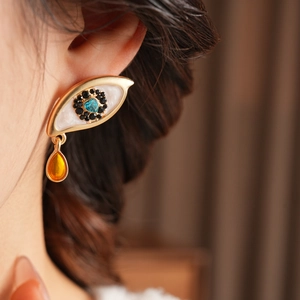 Macro shot of vintage gold eye earrings with blue heart gem and yellow crystal drop