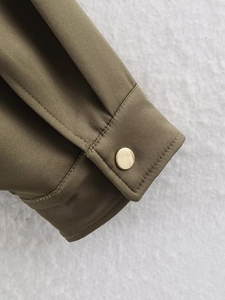 Macro detail of military green jacket cuff with a premium golden metal button
