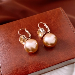 Macro detail of French vintage pearl earrings with sparkling crystal accents and gold finish