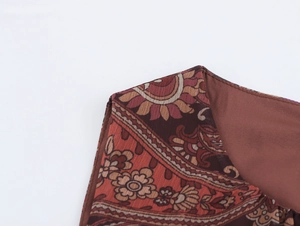Dettaglio dell'abito in chiffon con stampa paisley che mostra lo scollo e il tessuto rosso