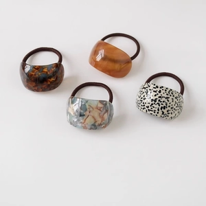 Close-up of four curved acetate hair ties featuring stylish tortoiseshell and marble patterns