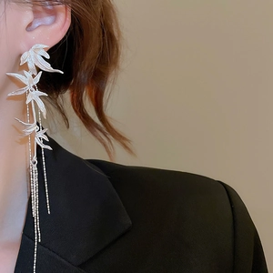 Detail of silver bamboo leaf tassel earrings worn by a model in a professional studio setting