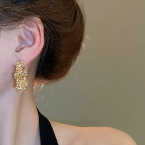 Close-up of gold star earrings with sparkling crystals and irregular textured finish