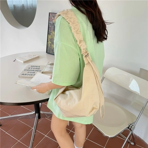 Dettaglio della borsa beige a pieghe stile dumpling con tessuto morbido e look casual