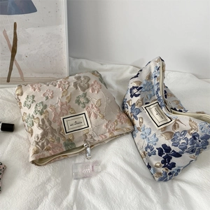 Détail de trousses à maquillage en jacquard floral avec étiquette Pleasant Time et zip