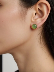 Close-up of a model wearing a green round jasper stud earring set in a gold silver frame