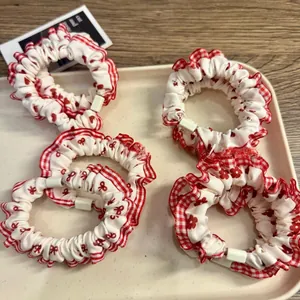 Close-up of red plaid scrunchies with floral patterns and ruffled edges in a dish