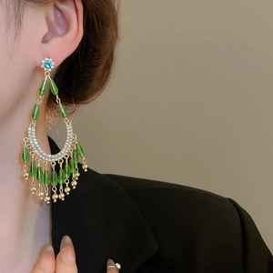 Vue macro détaillée de boucles d'oreilles à pampilles avec perles vertes et cristaux