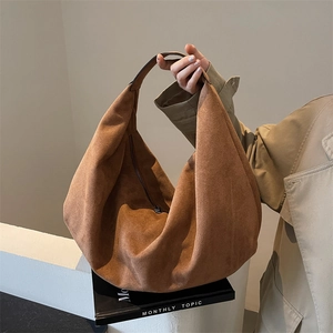 Minimalist brown matte leather large shoulder tote bag carried by a model on grey background